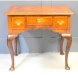 A George III burr walnut lowboy, with quarter veneered top above three frieze drawers, raised on