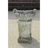 A stone garden urn raised on a rectangular plinth, 100cm high.