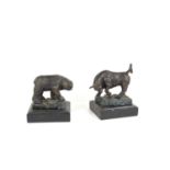 Two bronzed sculptures of a bison and a bull both standing upon a rocky outcrop and raised on marble