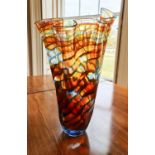 A large glass handkerchief vase, in graduated undulating shades of orange, blue and green.