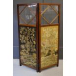 An early 20th century mahogany and glass fire screen set with two needlework panels depicting