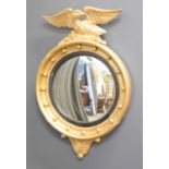 A late 19th century convex wall mirror with a surmounted eagle and gilt scrolling to the top and