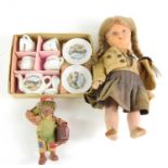 A vintage doll together with a miniature tea set.