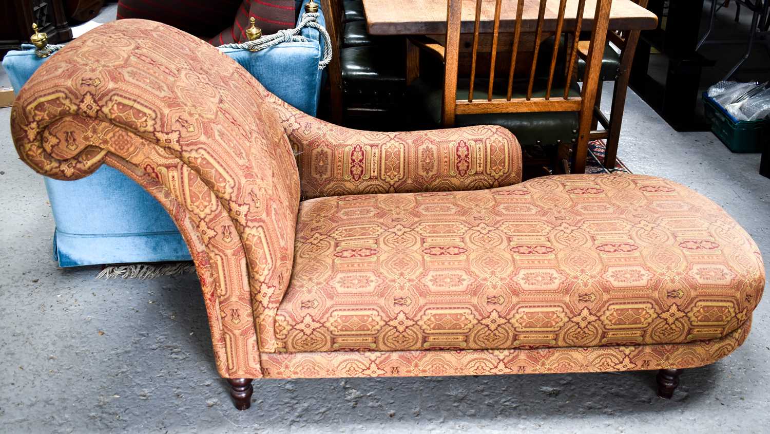 A modern chaise longue, in red and cream patterned upholstery, raised on mahogany turned legs.