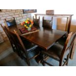 A 17th century style oak trestle table and matching chairs with leather backs and seats, the table