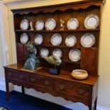 An 18th century oak Welsh dresser, the plate rack with shaped cornice and wavy frieze, over three