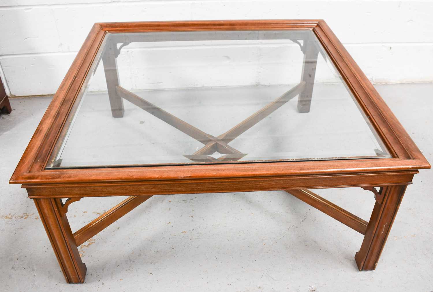 A modern mahogany glass top coffee table, with X-form base, 97 by 97 by 45cm.