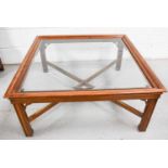 A modern mahogany glass top coffee table, with X-form base, 97 by 97 by 45cm.