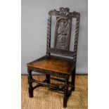 A late 18th/early 19th century hall chair, the back panel carved with a saint.