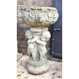 A reconstituted stone birth with twin cherub support and acanthus leaf design, 84cm high.