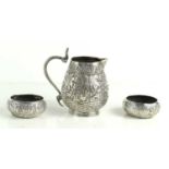 A pair of Indian silver salts together with a similar jug, each embossed with figural scenes.