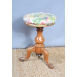 A Victorian adjustable piano stool with flower upholstery.