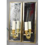 A pair of mirrored brass wall sconces, each with a single branch and candle bulb holder, 34 by 11½