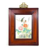 A Chinese hand painted porcelain plaque depicting birds and flowers set within a hardwood frame,