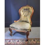 A Victorian walnut framed nursing chair with button back upholstery.and raised on castors.