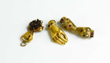 Two gold (tested as) clasps in the form of hands, set with stones together with a gilt metal example