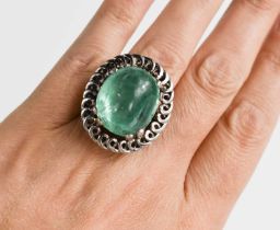An impressive 18ct white gold and boulder emerald ring, the stone bordered by decorative swirl