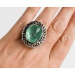 An impressive 18ct white gold and boulder emerald ring, the stone bordered by decorative swirl