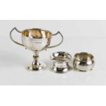 A silver twin handled trophy, Birmingham 1926, together with two silver napkin rings, 2.4toz total.