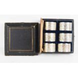 A set of six Chinese white metal napkin rings, 19th century, in the original box; A/F