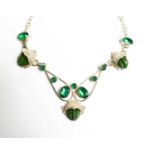 A silver, jade and emerald style necklace, with three face masks, united by decorative framework set