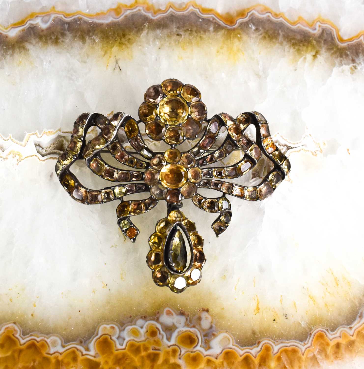 A Georgian silver and yellow gem set metamorphic brooch pendant, in the form of a bow with flower