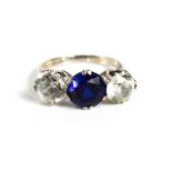 A 9ct white gold, platinum, sapphire and paste three stone ring, the central deep blue sapphire of