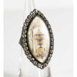 A Victorian white metal and paste mourning ring of marquise form, the enamel centre depicting an urn