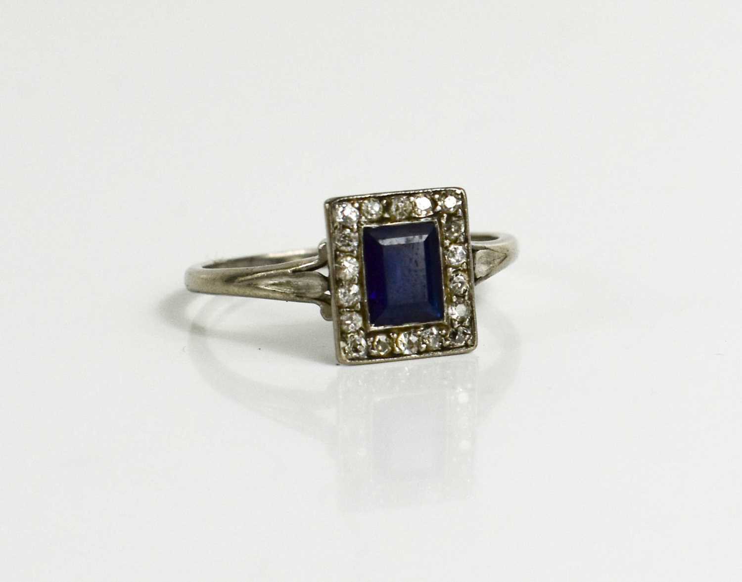 A white metal, diamond and sapphire ring, the rectangular cut sapphire bordered by chip diamonds,