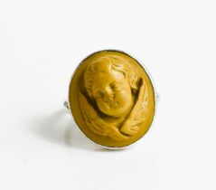A white metal ring, with relief moulded stone ring in the form of a winged cherub head, size N/O,
