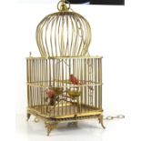 A Victorian style brass ceiling hanging birdcage with two birds and branches.