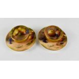 A pair of Royal Worcester miniature cups and saucers, painted with fruits to mossy ground, puce mark