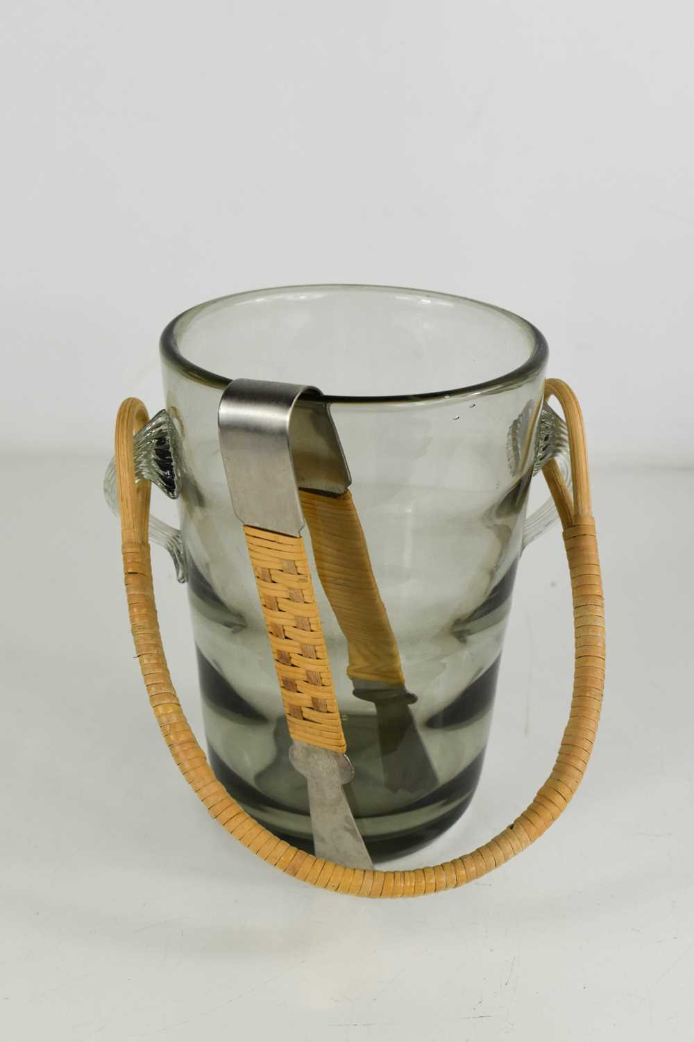 A Holmgaard smoky glass mid century ice bucket, with rattan handle and matching brushed steel pair