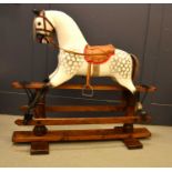 A vintage rocking horse on a pine stained base. the dapple grey hand painted horse with leather