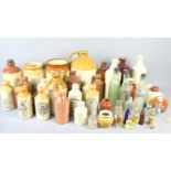 A large group of stoneware flagons and bottles together with some glass bottles to include