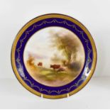 A Royal Worcester plate painted with lowland cattle in a landscape beside a lake, puce mark 1930s,