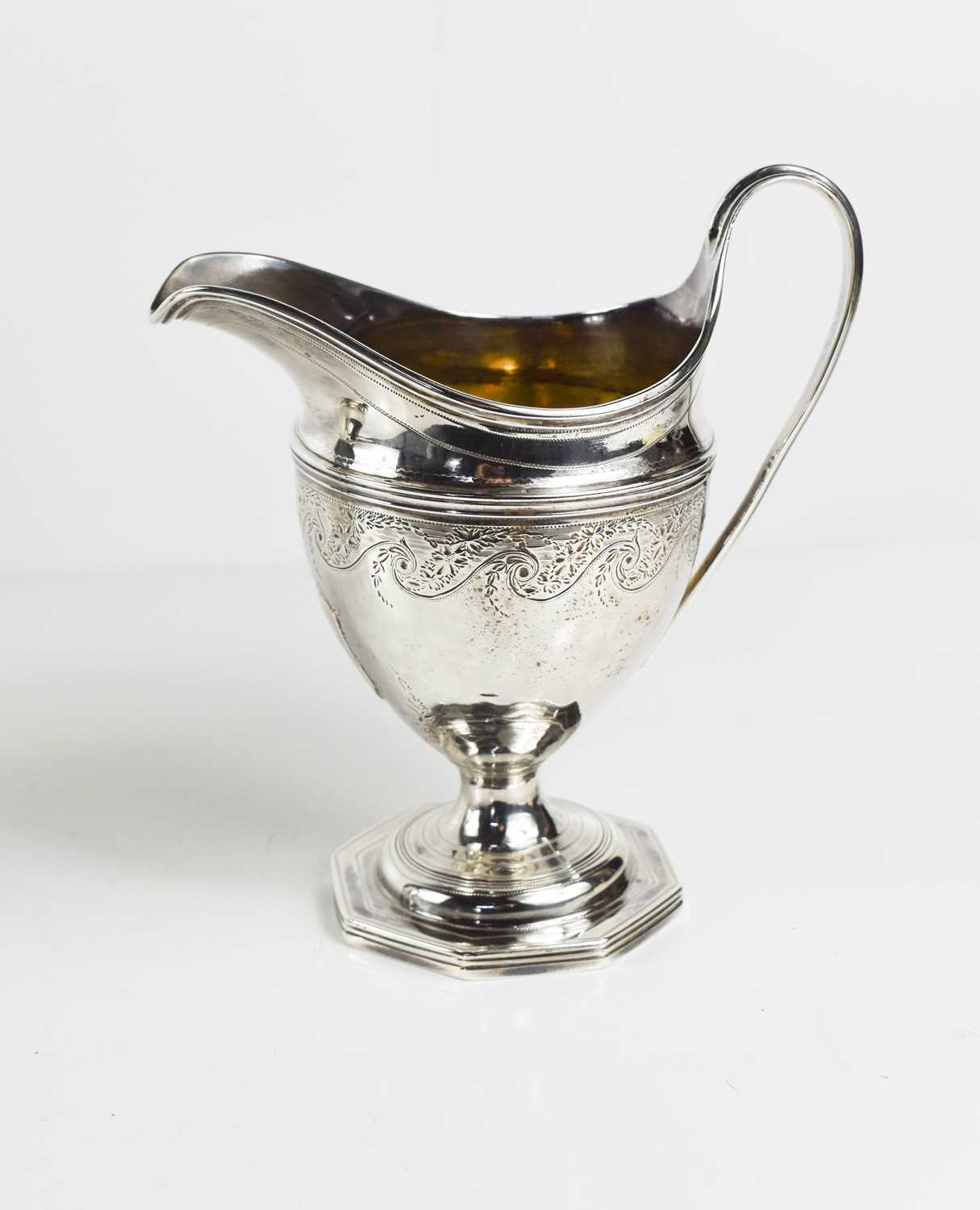 An 18th century George III helmet pedestal jug, with bright cut engraved decoration of garlands