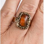 A 12ct gold Georgian ring, set with an agate cabochon bordered by floral worked setting, on an