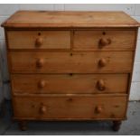 An antique pine chest of drawers, with two short over three long drawers, raised on turned knop