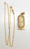 An Egyptian gold pendant, with central lozenge set with hieroglyphs, with filagree border, unmarked,