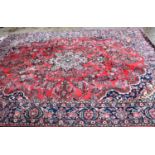 A large wool rug of Persian design, the red ground with central lozenge and foliate and arabesque