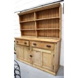 A large antique pine dresser and rack, the enclosed rack having two shelves bearing cup hooks and