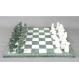 A green and white marble chess board and pieces.