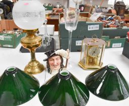 A brass paraffin lamp with glass shade, a mantle clock, a character jug and brass ceiling light with