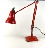 A red anglepoise lamp by Herbert Terry & Sons.