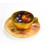 A Royal Worcester miniature cup and saucer, painted with fruit to a mossy ground, the saucer