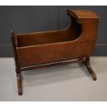A 19th century mahogany childrens cradle, with canopy hood, and raised on shaped feet, rocks from