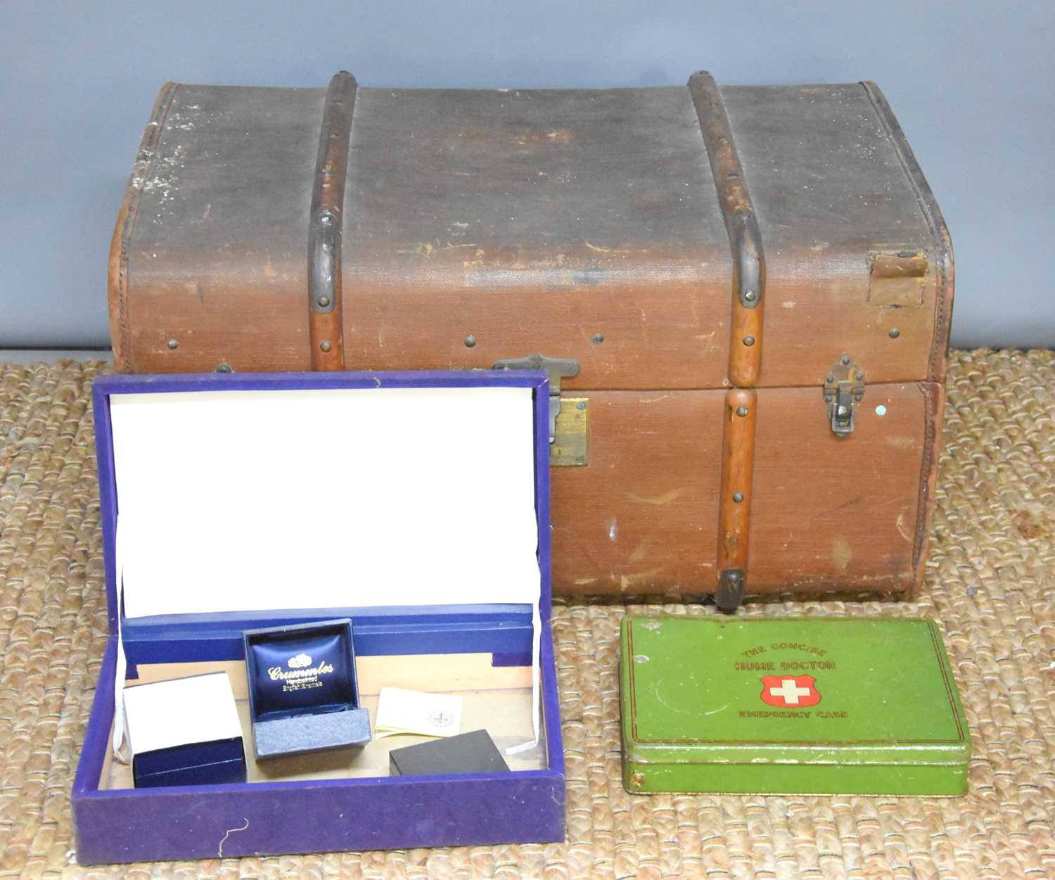 A vintage leather bound steamer trunk together with a vintage first aid tin and some jewellery