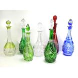 Seven cut glass decanters of different colours and forms.