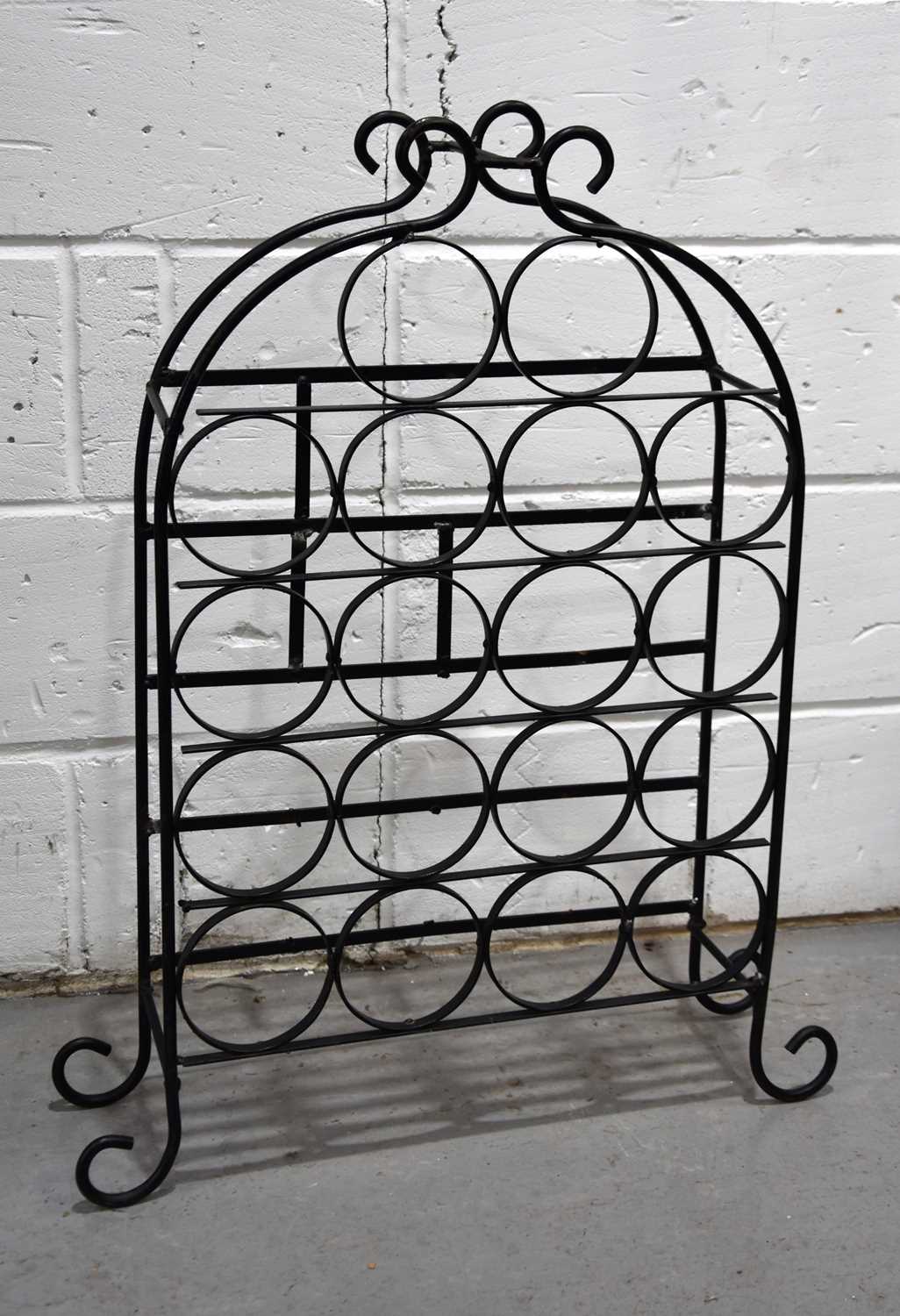 A wrought iron wine rack for eighteen bottles raised on scroll feet.